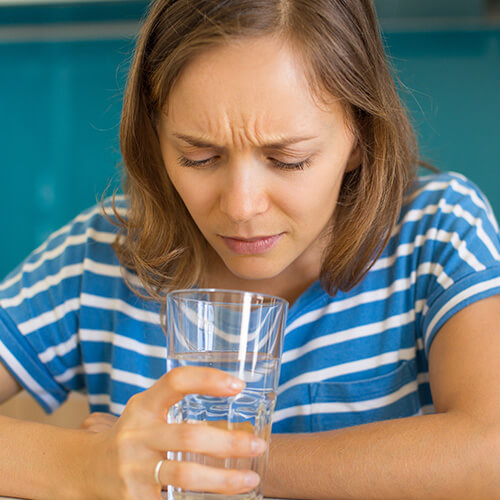 woman looking suspiciously at water because it smells like rotten eggs