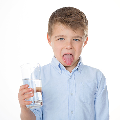 boy making face about water in glass
