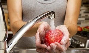 Person washing apple in sink