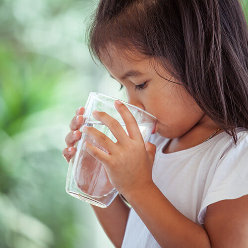 A girl drinks a glass of reverse osmosis (RO) water because her parents discovered how much of a value an RO system is.