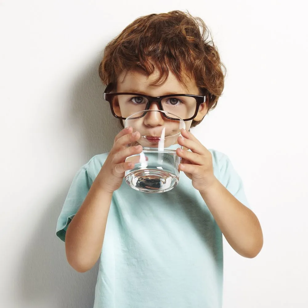 little boy drinking water from glass