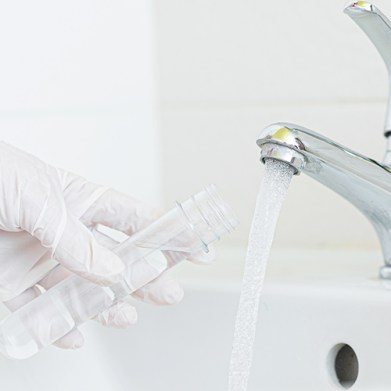 Tap water analysis quality control concept. Hand with a flask and water tap ckose up.; Shutterstock ID 1568600659; team: Editorial; job: ; client: Culligan; purchase_order: Liam Green