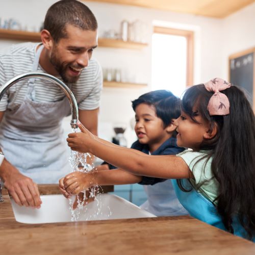 dad and daughters using well water from kitchen tap
