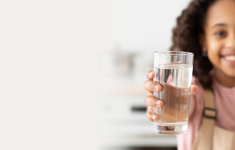 Girl drinking glass of fresh filtered water from dispenser