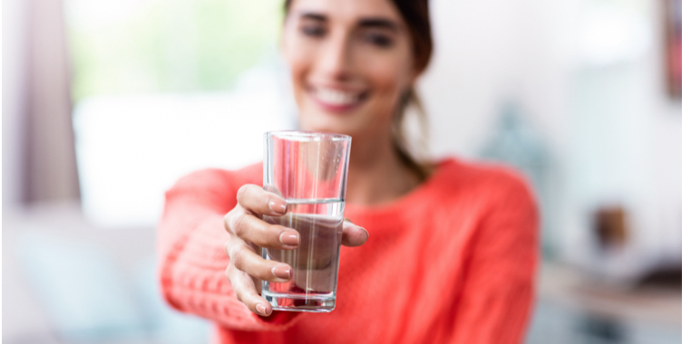 Woman holding glass of clean cold dispensed water