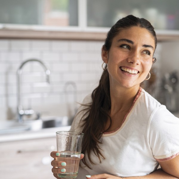woman drinking tap water in kitchen